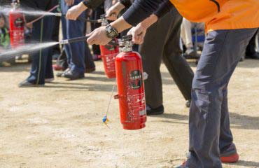 Closeup of a group of people using fire extinguishers in a safety class