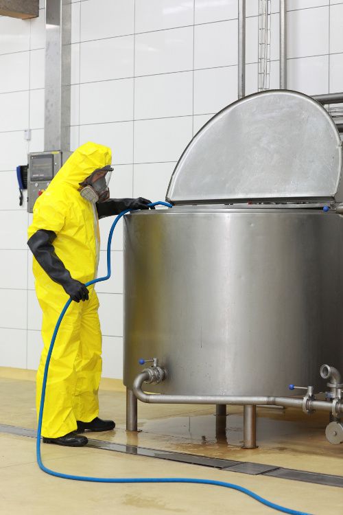 A food chemical safety image of a worker cleaning equipment.
