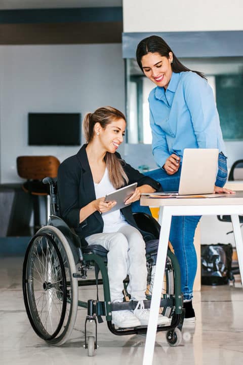 Latin woman in wheelchair working with computer in office